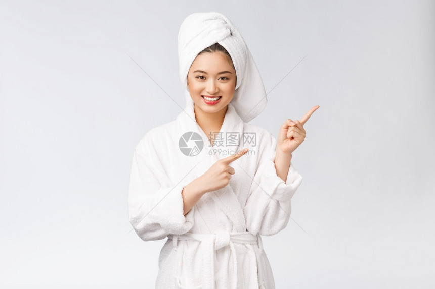 年轻女美容肖像显示并指向空的复制间浴袍中的亚洲美图片