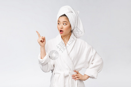 年轻女美容肖像显示并指向空的复制间浴袍中的亚洲美图片