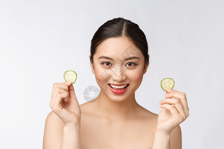 美丽的亚洲女子拿着黄瓜片微笑图片