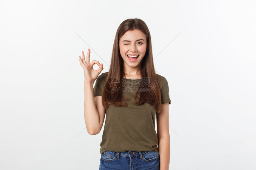 快乐的年轻女用手指显示好牌子在灰色背景上被孤立的眨眼快乐年轻女用手指显示好牌子在灰色背景上被孤立的眨眼子图片