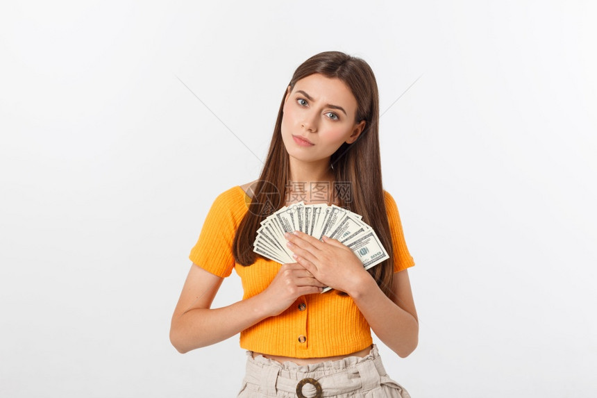 快乐的年轻女身处灰色背景一边看持有钱和信用卡一边看快乐的年轻女身处灰色背景图片
