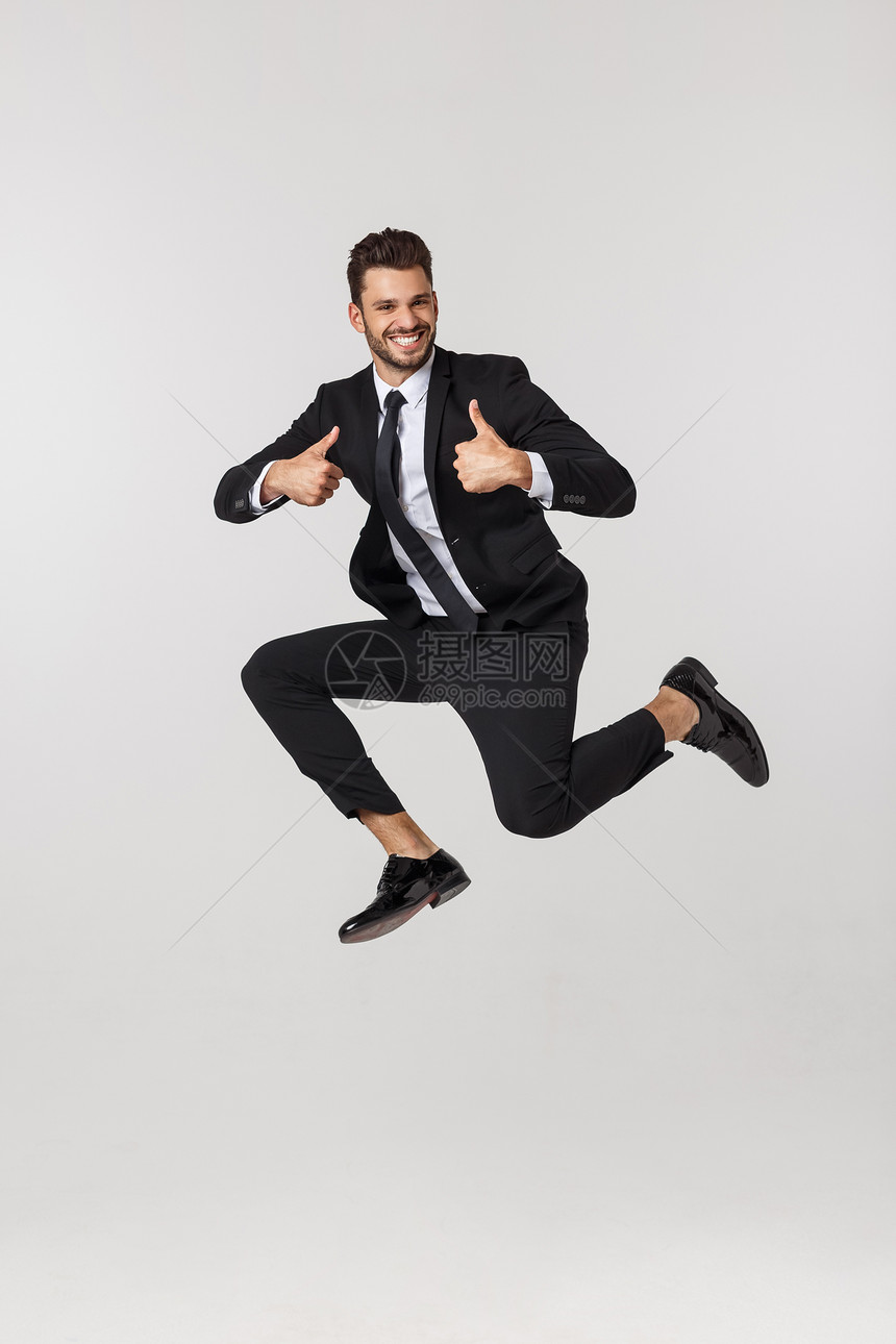 一个快乐的商人在孤立白色背景下空中跳跃的肖像图片
