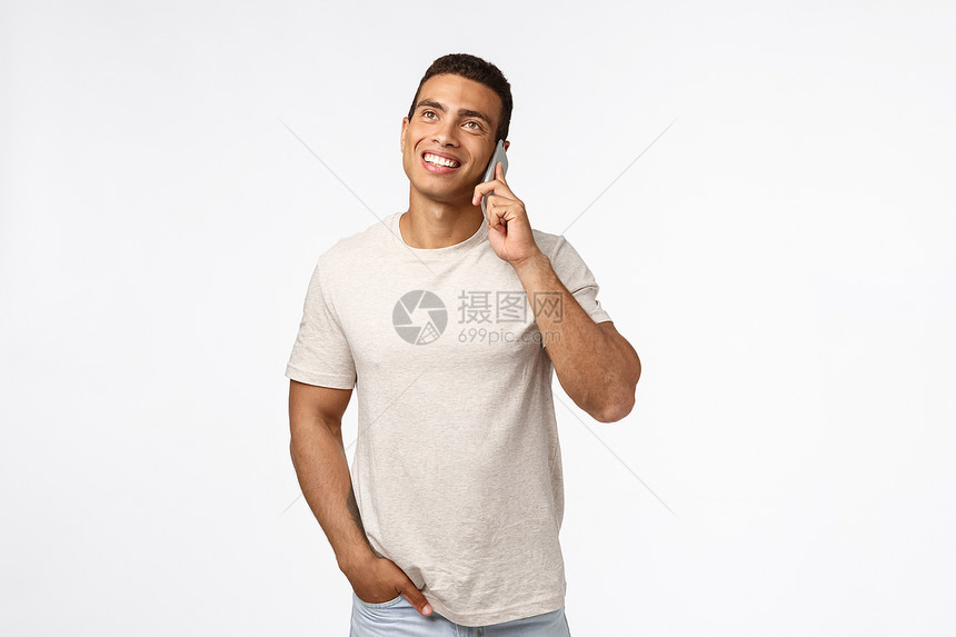 快乐笑的青年男子穿着t恤与朋友交谈热情地抬头手握在口袋里轻地智能手机按在口袋里说话愉快地白背景笑的青年男子穿t恤衫抬起热情的表智图片