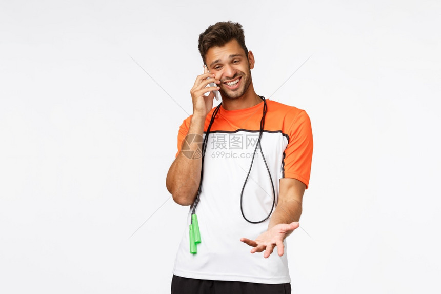 令人惊讶和快乐笑的帅运动员在训练课期间通过电话交谈围着跳绳在脖子上说话举起惊吓的手讨论一些有趣的事情在电话上图片
