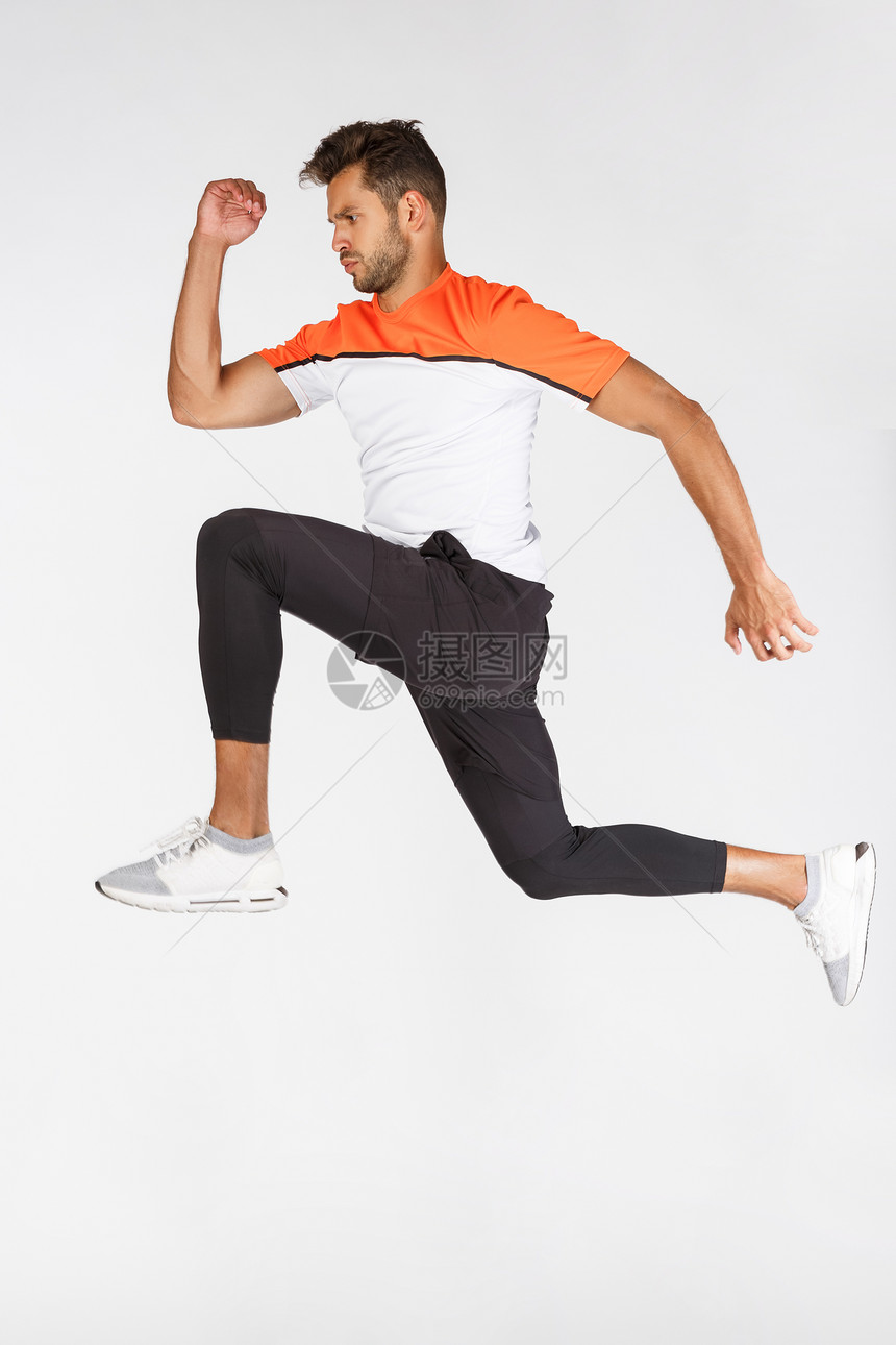 运动中的员有吸引力的年轻足球运动员跳在空中跑步看重点和决心体育设备或广告白背景运动中的垂直全长运动员跳球白背景图片