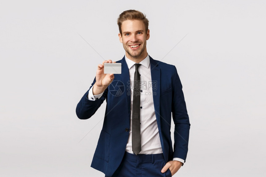 英俊幸运成功具有经典西装的商人用信卡支付持有银行展示其快乐和微笑进入机场休息区站立白色背景英俊具有经典西装的商人用信卡支付站立白图片