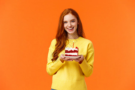 合伙人黄色女孩在黄色毛衣上站立橙背景女朋友在黄色毛衣上狂欢派对带一块蛋糕和根蜡烛庆祝伴侣生日唱着快乐的b日笑着可爱站在黄色毛衣上的橙背景背景