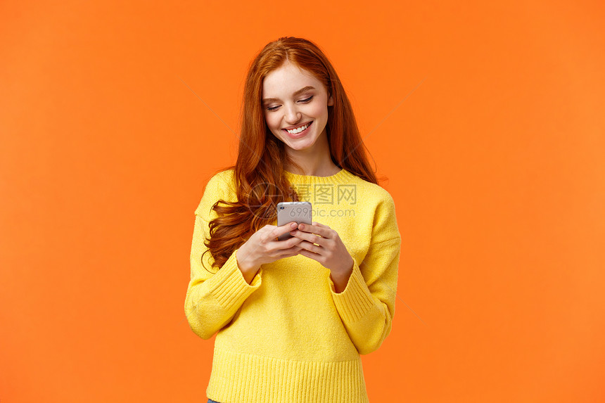聊天沟通人与聊天概念无照顾的现代时装女孩编辑照片在智能手机应用程序上过滤器编辑照片使用聊天应软件微笑看移动显示橙色背景通信人与聊图片