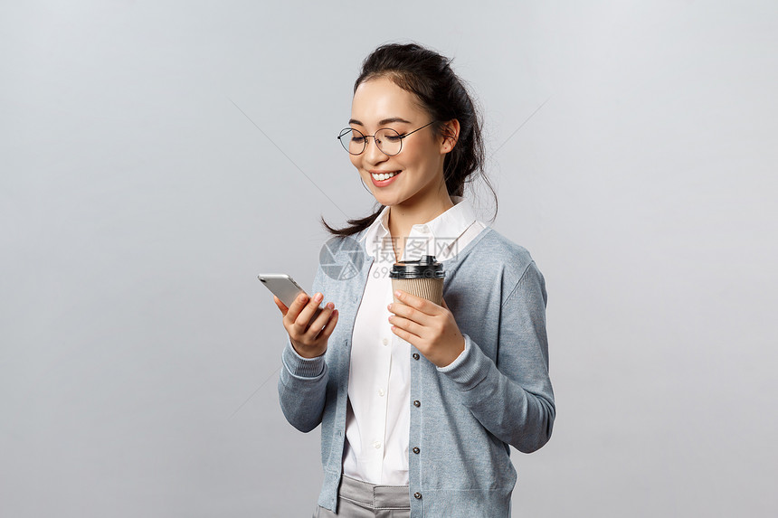 带着眼镜的女孩一只手拿咖啡一只手拿手机图片