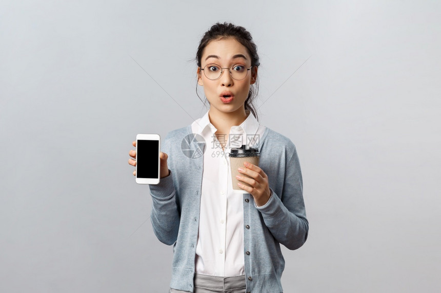 带着眼镜的女孩一只手拿咖啡一只手拿手机图片