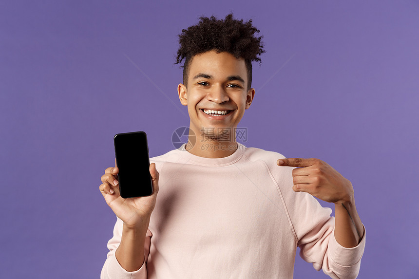 年轻英俊男子在网上推广智能手机应用程序或购物在互联网上提供货物用手机指向显示和微笑的喜悦建议年轻英俊男子在网上推广智能手机应用程图片