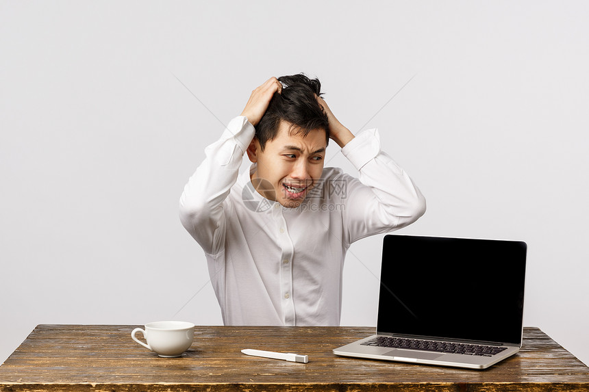 惊慌和的人从头上拉发坐不安和焦虑有巨大的问题用焦虑紧张的表情盯着笔记本电脑坐在办公室的白色背景惊慌和的人从头上拉发坐不安和痛苦在图片