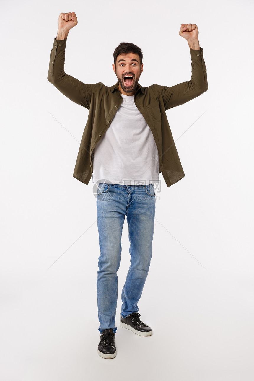 成功就和胜利概念垂直全拍的欢快和乐胜利的年轻胡子男穿牛仔裤和大衣举起手来呼赢得姿态庆祝伟大的新闻垂直全拍的欢快和乐举起手高庆祝伟图片