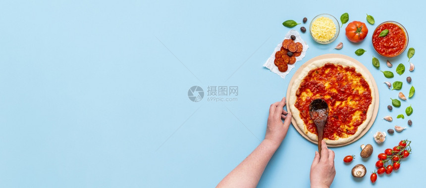 无法辨认的女人把番茄酱放在手伸的披萨面团上在家里做经典披萨配上新鲜的原料图片