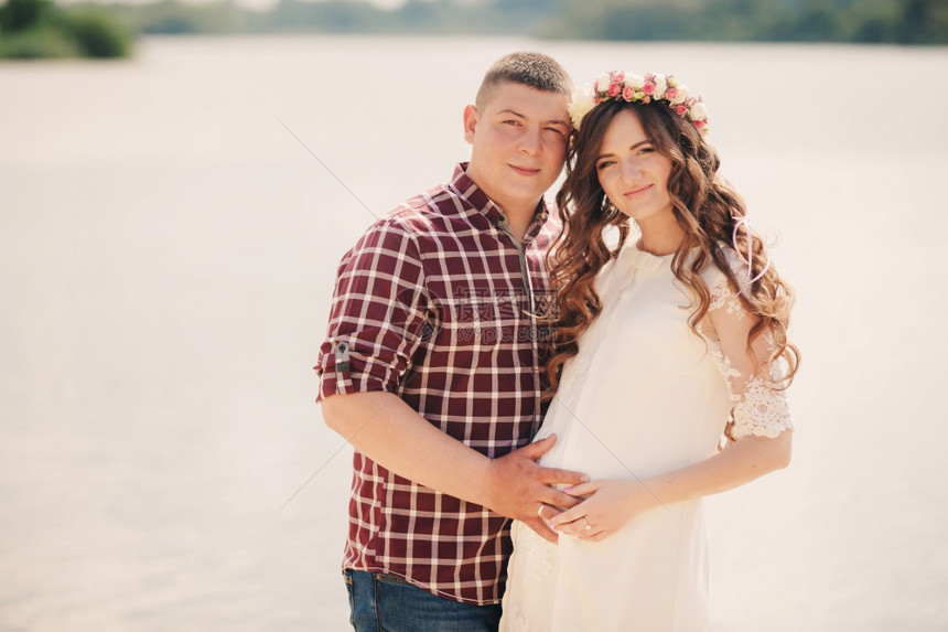 怀孕夫妇在湖边拥抱图片