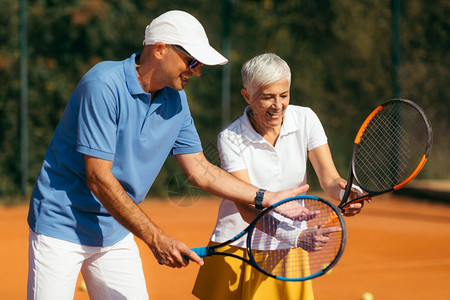 网球教官和高级女子一起上粘土场网球课的女人背景图片