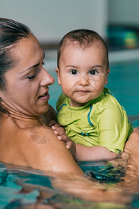 在游泳池中母亲和婴儿男孩在游泳池中图片
