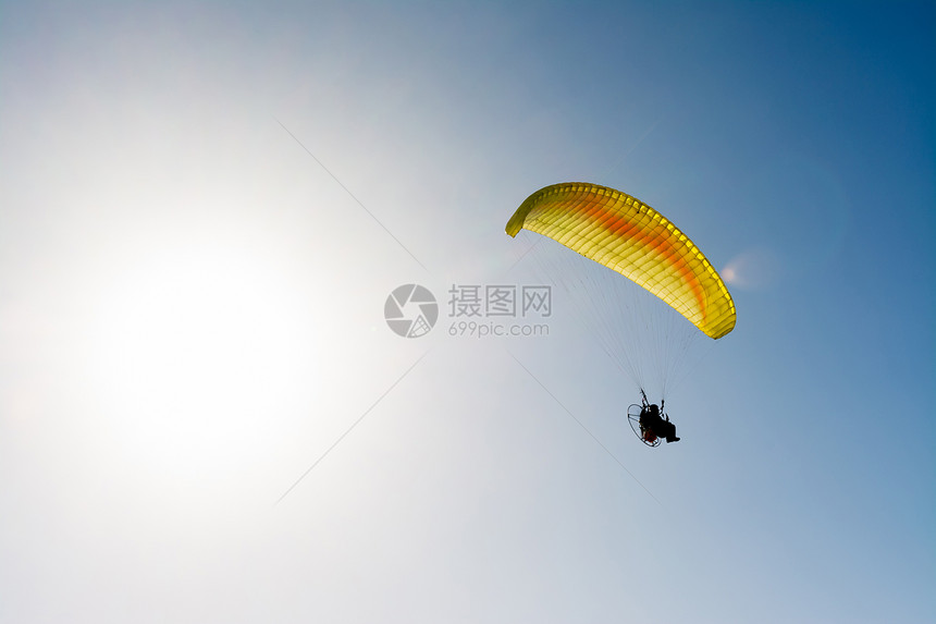 滑翔伞在蓝色天空上与抛光机一起飞行图片