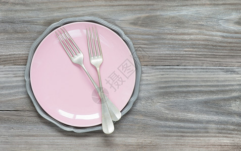 粉红色空板上的两个旧叉子上面是灰色木本面的空粉红色板块带有复制空间背景图片