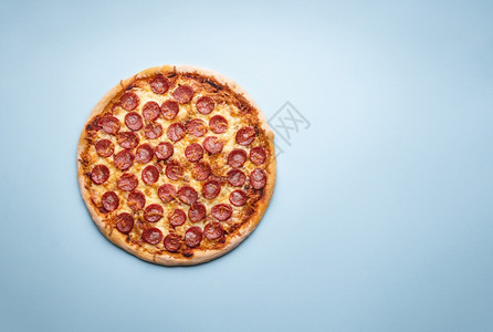 蓝色背景的全披萨新鲜家烤披萨配有马扎里拉和辣椒背景图片