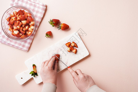 在粉红色桌上的切片板草莓果实的女子手切草莓果实图片