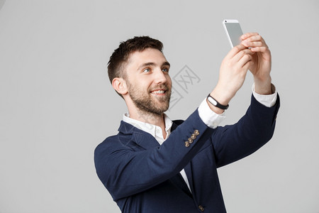 商业概念肖像英俊的商人带着智能手机自拍白色背景图片