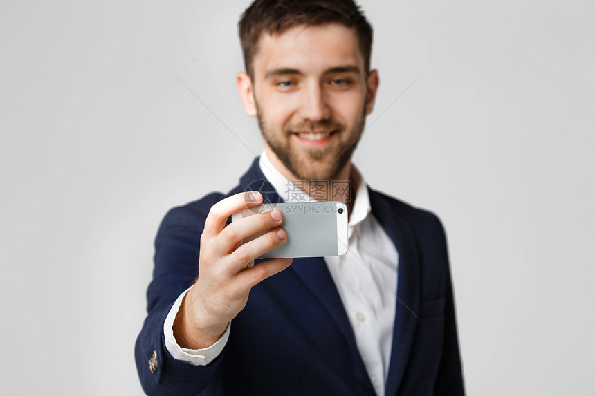 商业概念英俊的商人用智能手机自拍白色背景图片