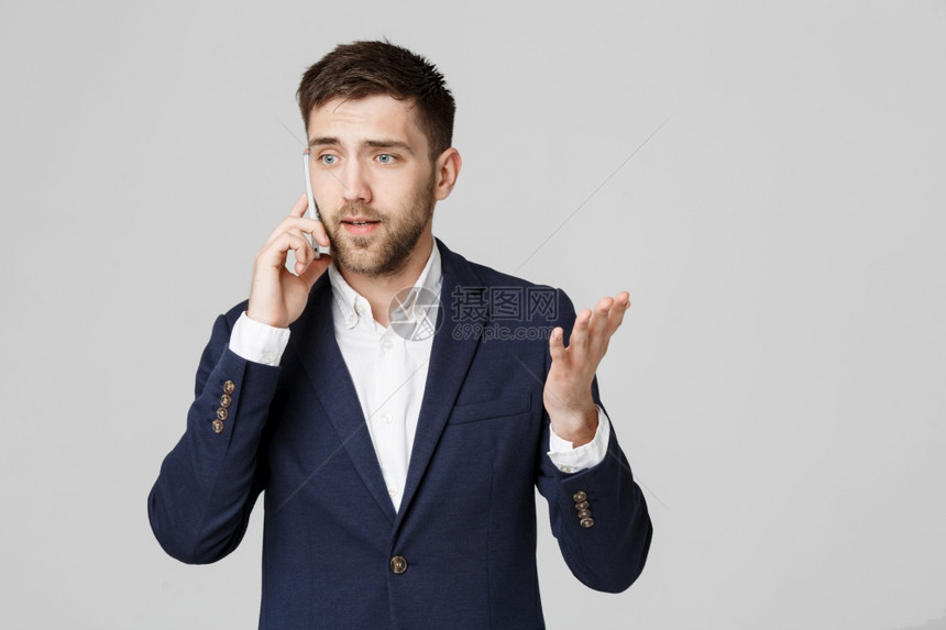 商业概念肖像年轻英俊的愤怒商人穿着西装在电话里聊天看着相机白色背景图片