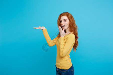 姜黄色头发快乐的姜红发女孩头像手指向外令人震惊的表情面部蓝色背景复制空间乐趣和人的概念手向外复制空间背景
