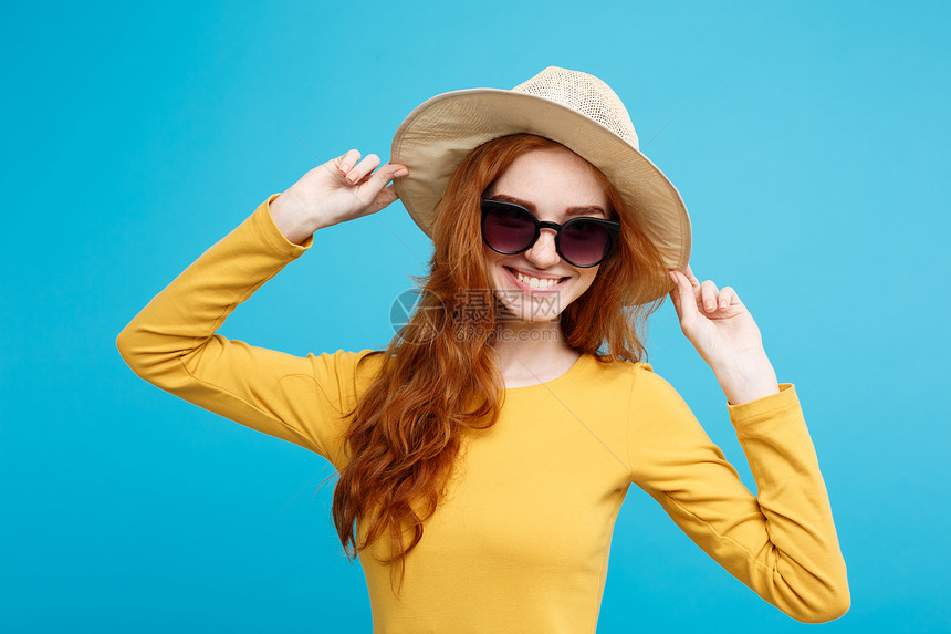 旅行概念关闭肖像年轻美丽的红头发女孩时髦的帽子和墨镜微笑蓝色的面部背景复制空间图片