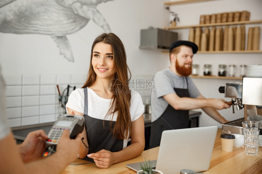 女咖啡师为持信用卡的客户提供支付服务图片