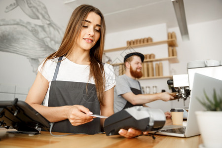 女咖啡师为持信用卡的客户提供支付服务图片