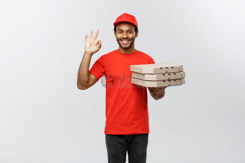 英俊的非洲比萨饼送货员的肖像以灰色工作室背景隔离复制空间交付概念英俊的非洲比萨饼送货员的肖像以手指分隔图片