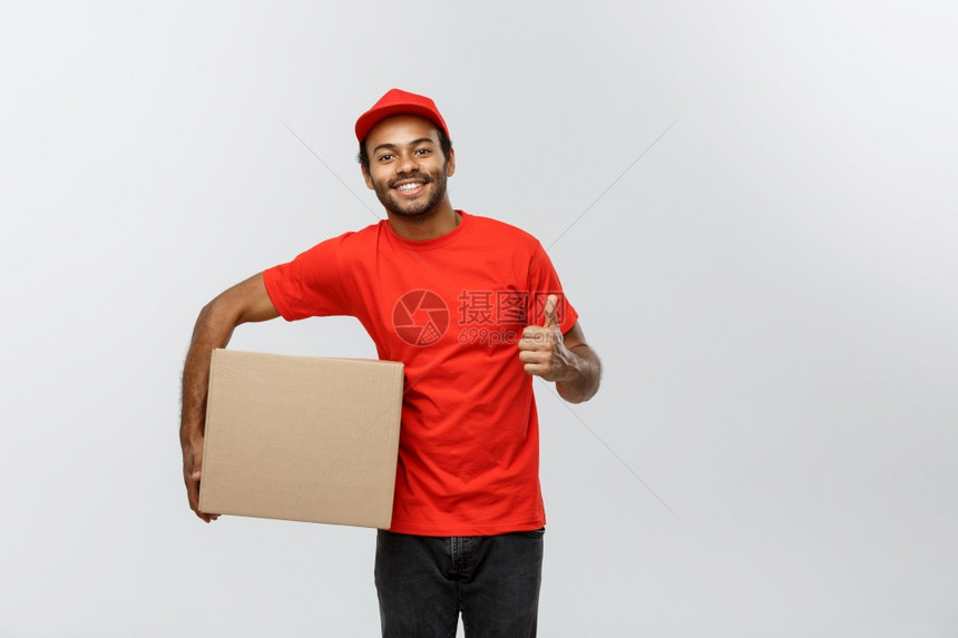 交付概念快乐的非洲送货员肖像他拿着一个盒子包并展示出震动孤立在灰色工作室背景上复制空间快乐的非洲送货员肖像显示震动复制空间图片