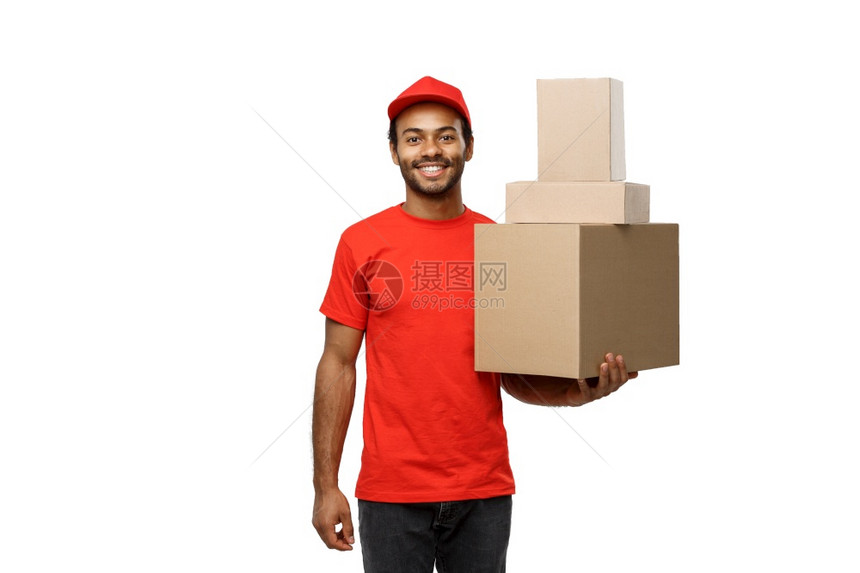 交付概念身着红布的非洲快乐送货员的肖像身着一盒子孤立在白色工作室背景上复制空间身着一盒子的非洲快乐送货员的红布肖像身着白色工作室图片