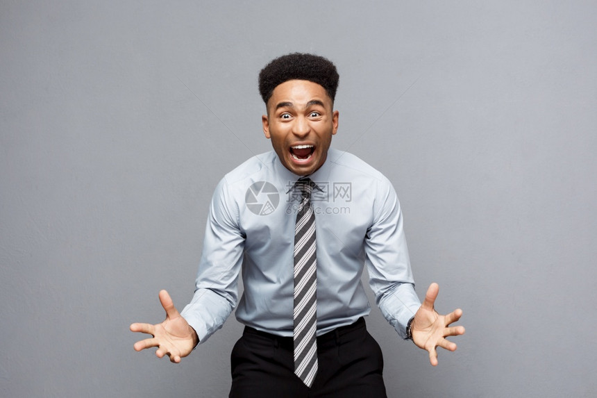 商业概念自信快乐的年轻非洲美国人在他面前举手表示对灰色背景的失望图片