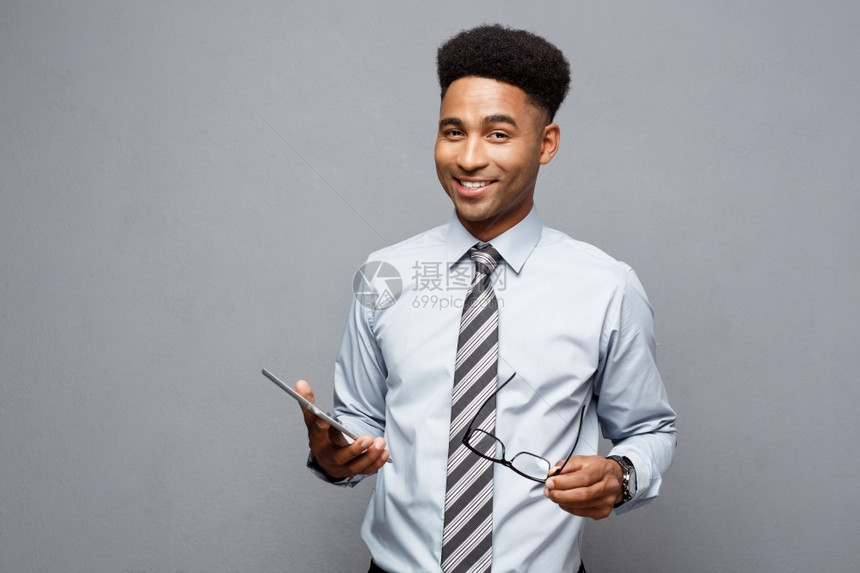 商业概念快乐的英俊专业非洲商人持有数字平板电脑并与客户交谈图片