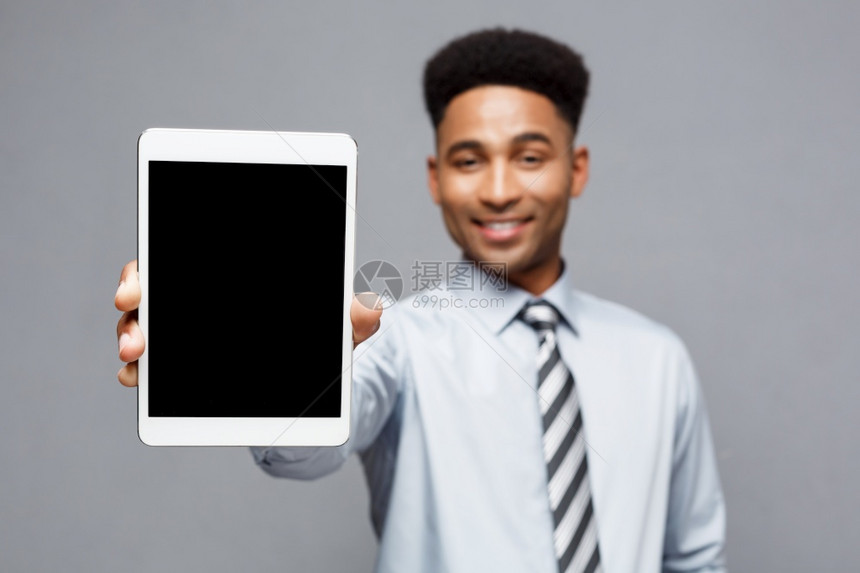 商业概念快乐英俊的非洲专业商人向客户展示数字平板电脑图片