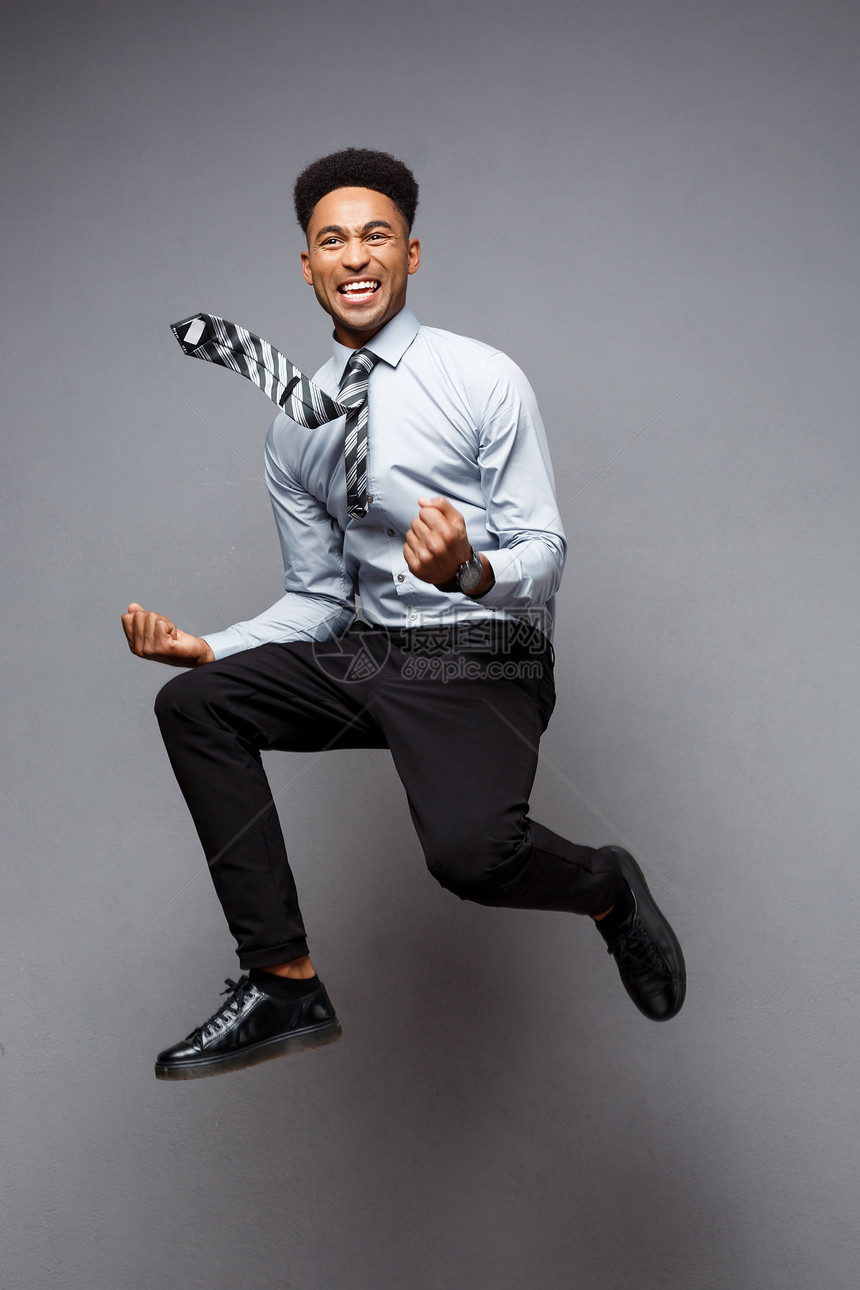 商业概念成功的非裔美国商人在办公室快乐跳跃的完整肖像图片