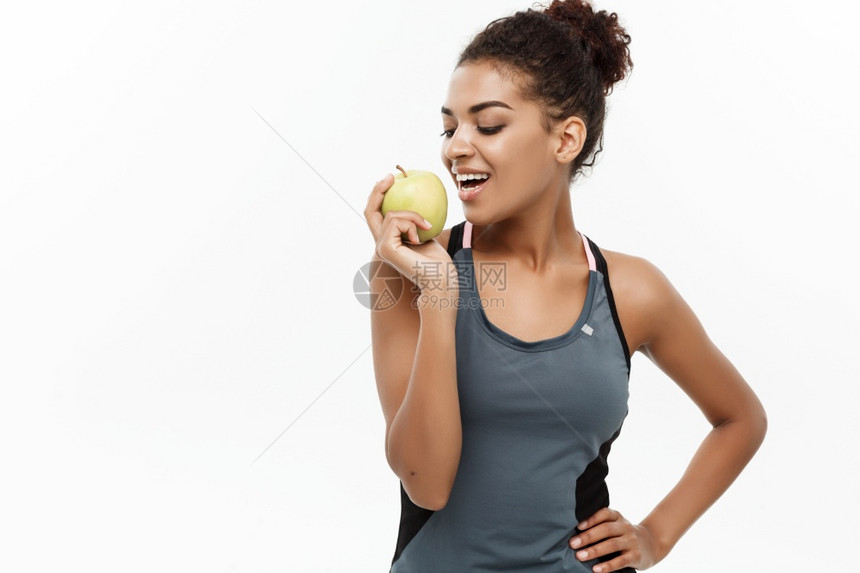 健康和概念美籍穿灰色运动服的美籍女士吃着绿苹果孤立在白色背景上健康与概念美籍穿灰色运动服的美籍女士孤立在白色背景上图片