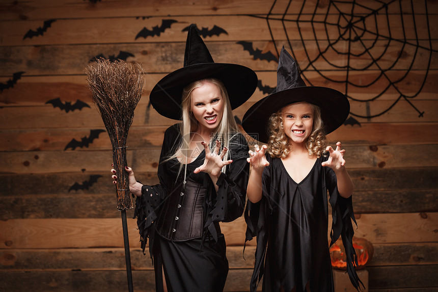 halowen概念快乐的母亲和女儿穿着巫服庆祝halowen装扮有弯曲南瓜的圣殿在木制工作室背景上的蝙蝠和蜘蛛网之上打扮成弯曲南图片