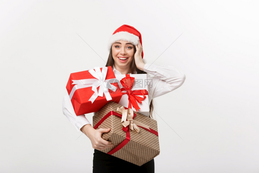 商业概念美丽的天主教青年女商人戴着圣塔帽拿许多圣诞礼物盒上面还有复制空间图片