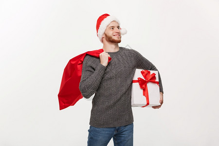 圣诞概念年轻快乐的胡子男拿着圣塔包和白礼物图片