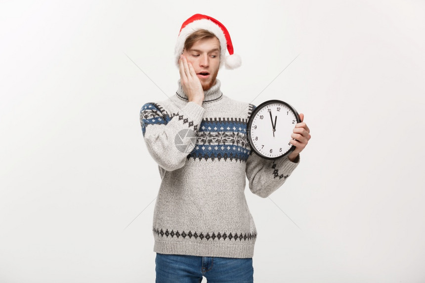 假期概念年轻快乐的英俊长胡子男穿着毛衣白色时钟工作室背景图片
