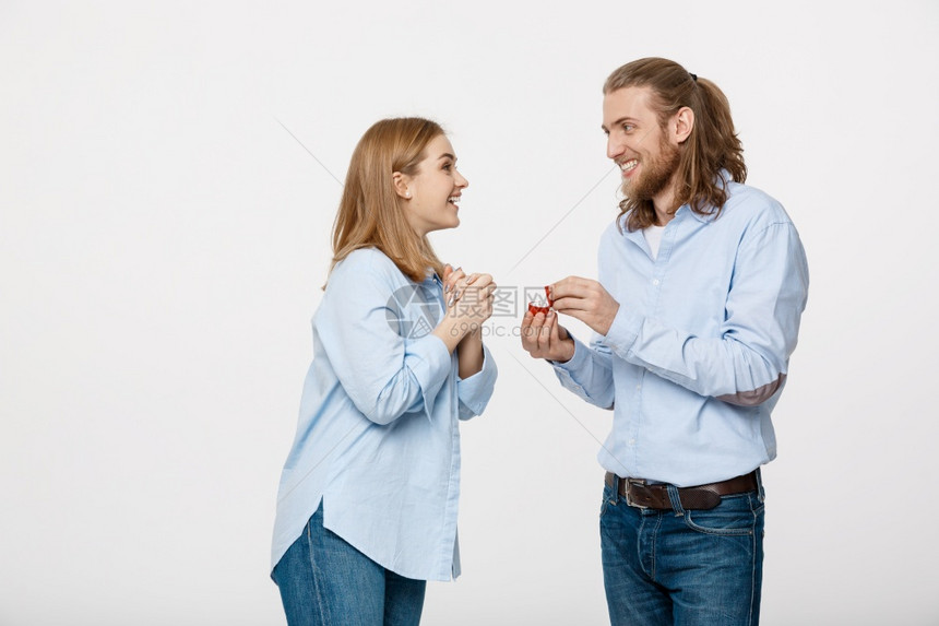提议概念男人的肖像显示订婚戒指钻石给他的漂亮女友超过孤立的白色背景显示订婚戒指钻石给他可爱的女朋友图片