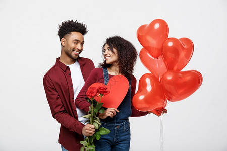 年轻有吸引力的非洲夫妇和红玫瑰心胸气球约会图片