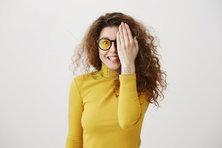 站在灰墙上被孤立的年轻女孩在灰墙上围着镜头玩耍微笑着女孩站在灰墙上图片