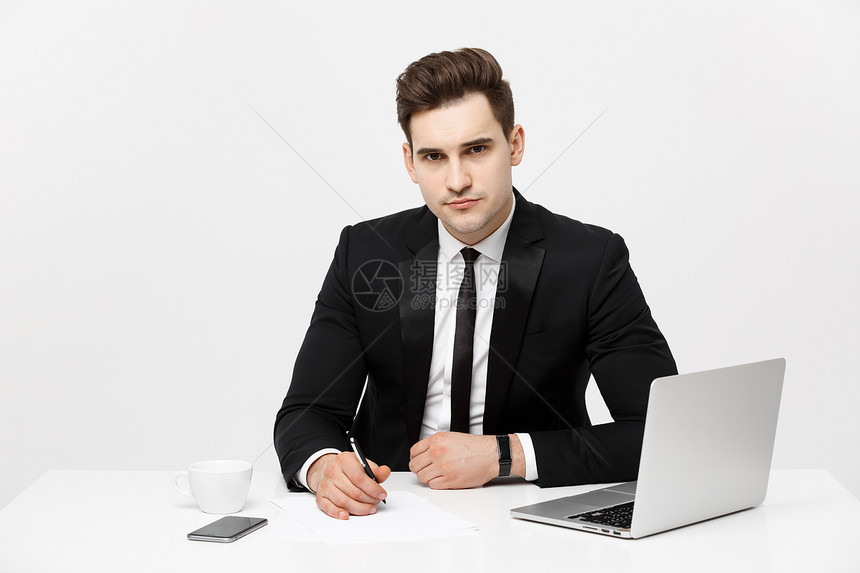 坐在办公桌旁的自信经理肖像看着相机在电脑上工作的商人肖像在新的现代化办公室中成功的正式人肖像坐在办公桌和看相机的自信经理肖像图片