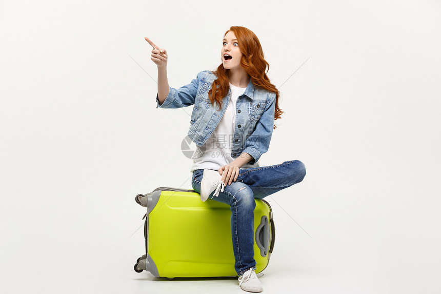 旅行和生活方式概念年轻的天主教妇女坐在手提箱上指向前进的方旅行和生活方式概念年轻的天主教妇女坐在手提箱上指向前进的方图片