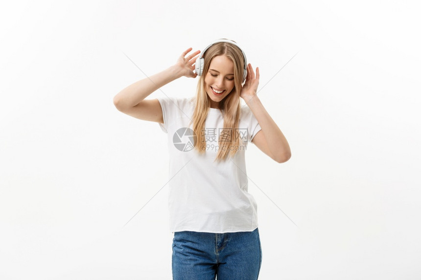 生活方式概念快乐的女学生用耳机听音乐的肖像却在孤立的白色背景下跳舞生活方式概念快乐的女学生用耳机听音乐的肖像在孤立白色背景下跳舞图片